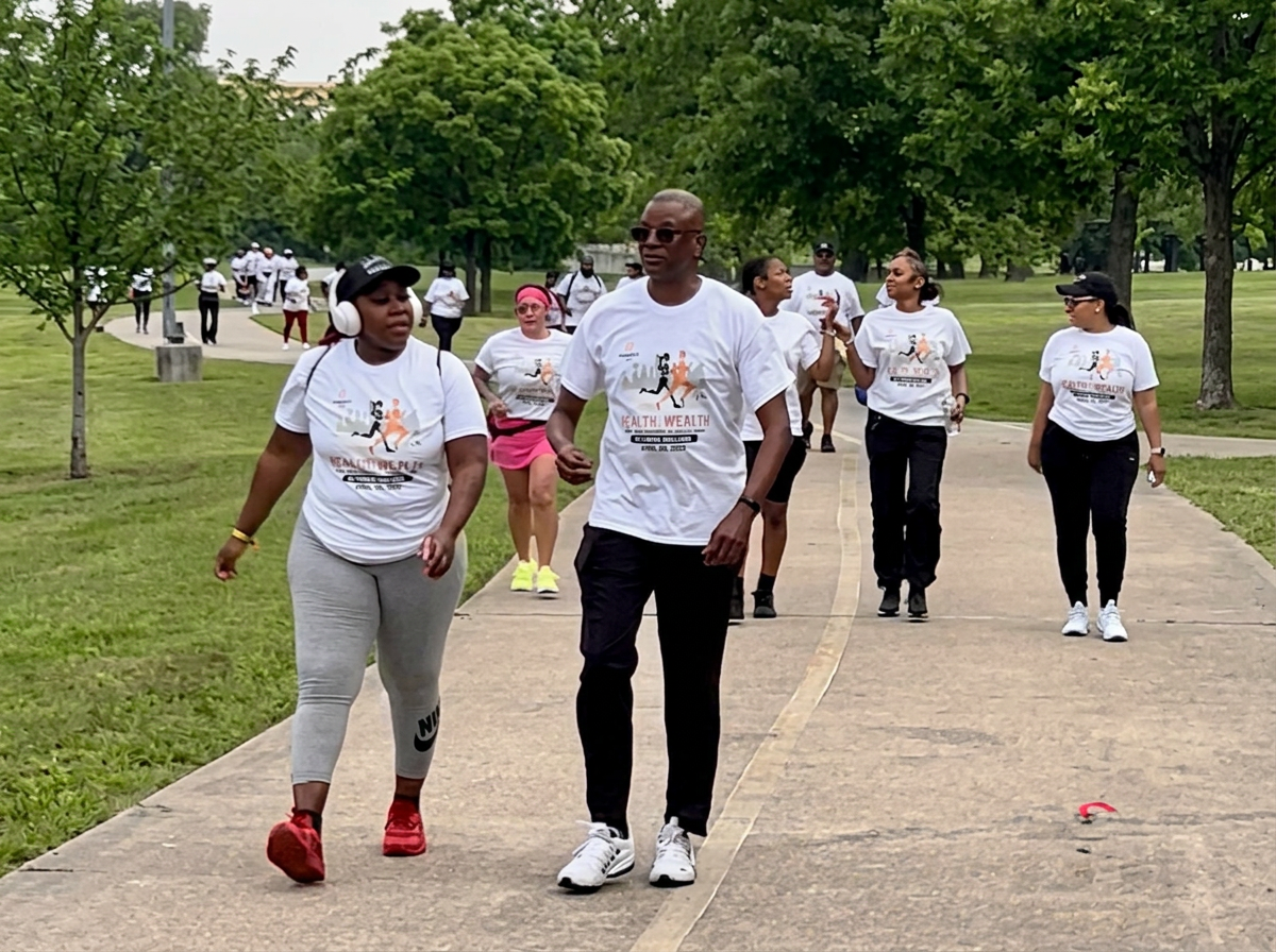 Corey Artis walking alongside community members at the Health & Wealth Walk